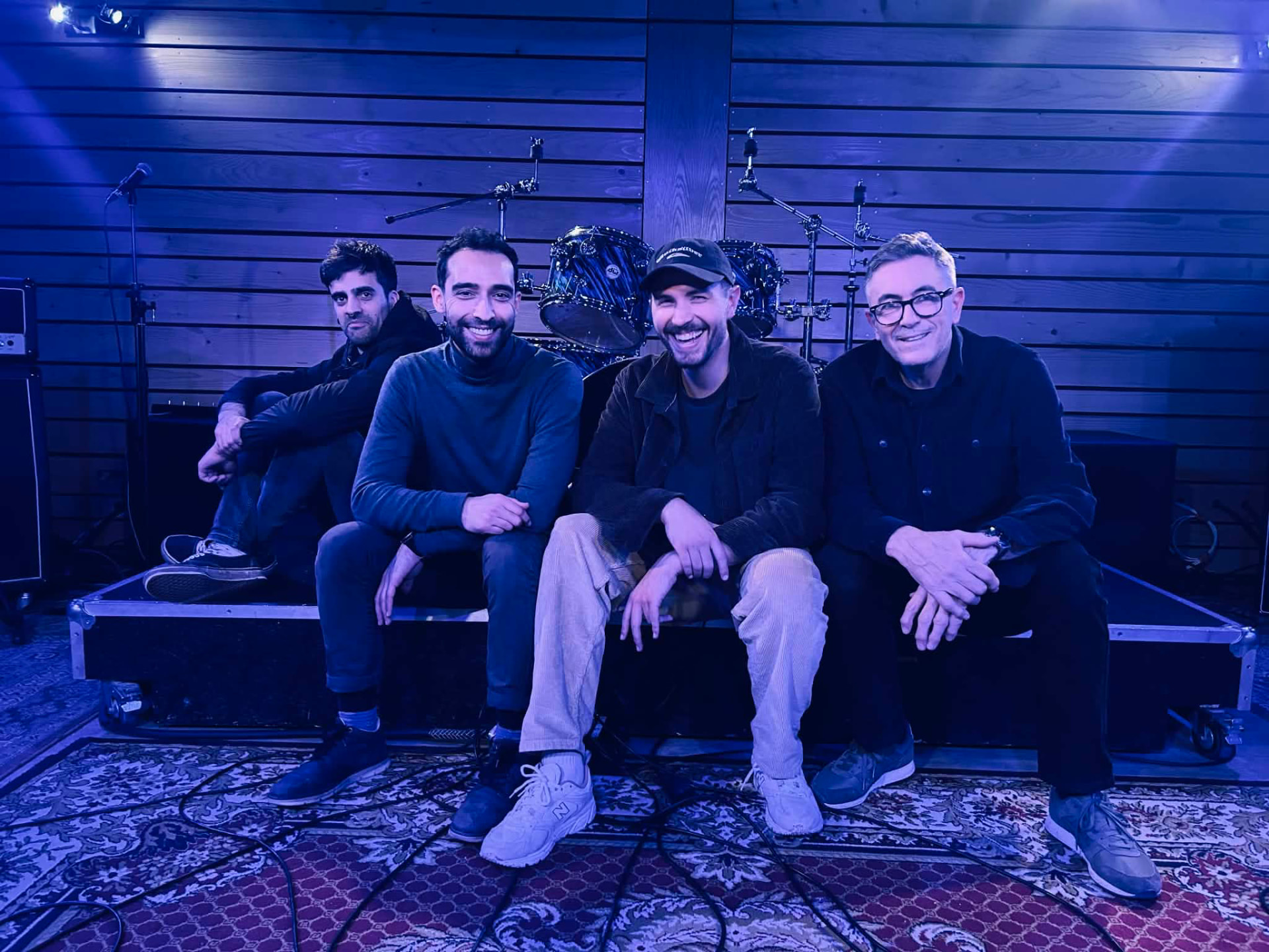 Les quatre membres de Rue Salazar assis sur scène en studio, lumière bleue
